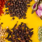 top view of heaps of spices and herbs on a yellow background